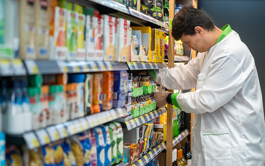 Employee restocking products in a supermarket shelf (photo)