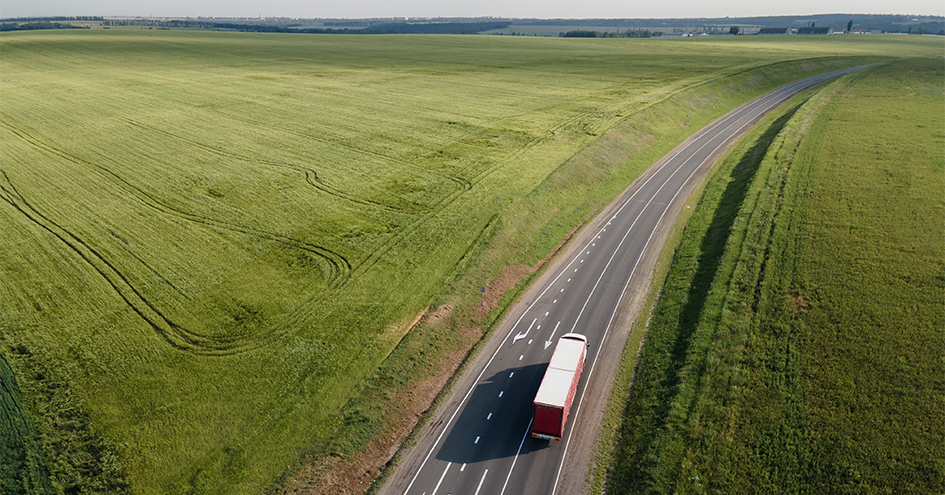 A single truck driving on an empty road through vast agricultural fields (photo)