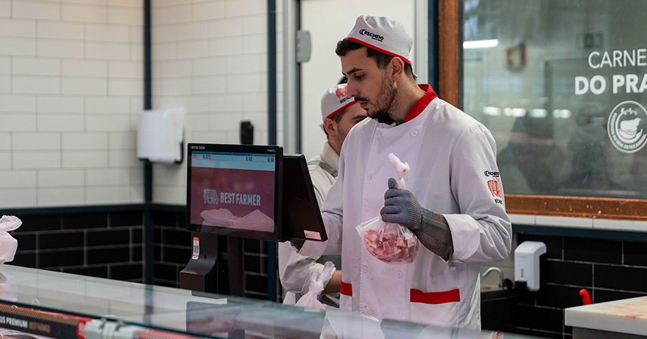 Employee with a bag of diced meat typing on a screen (photo)