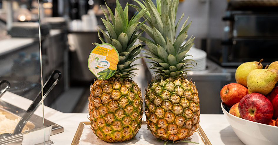 Two pineapples on a counter next to a bowl with apples and pears (photo)