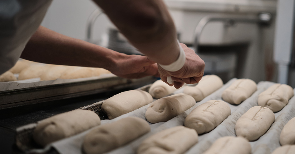 Baker preparing bread on a tray before it is baked (photo)