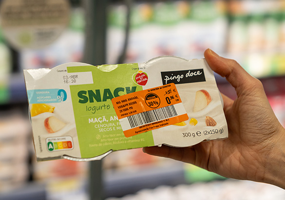 Person holding a package of yoghurt with an orange sticker indicating a reduced price  (photo)