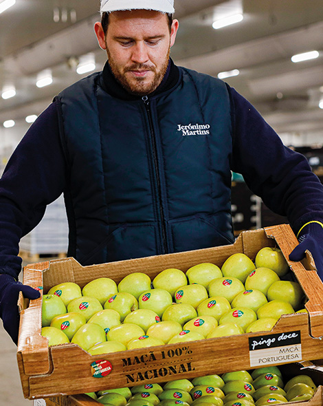 Employee holding a crate of green apples (photo)