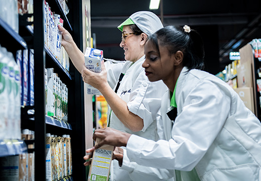 Female employees replenishing milk alternatives into a shelf (photo)