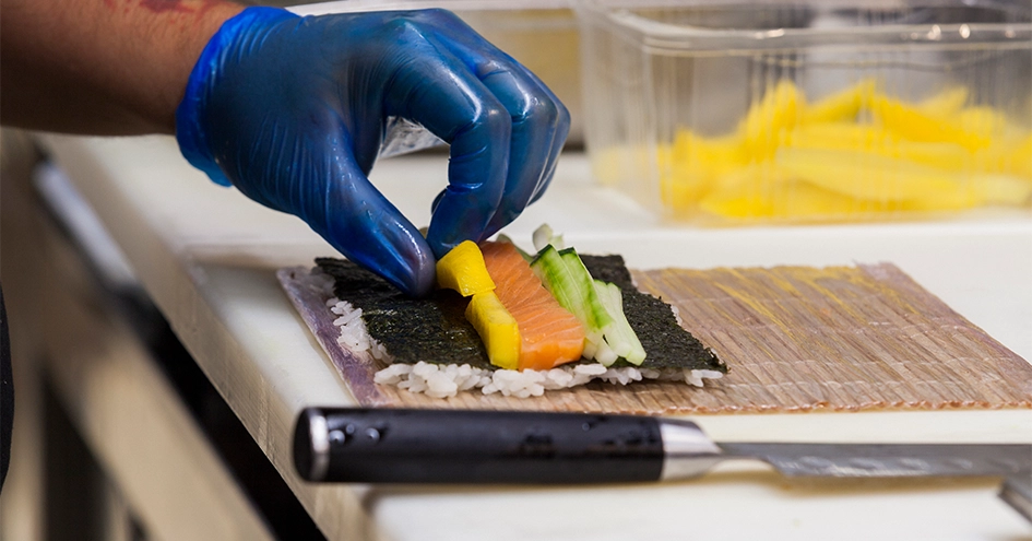 Close-up of a hand preparing sushi (photo)