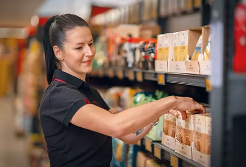 Employee arranging products in a supermarket shelf (photo)