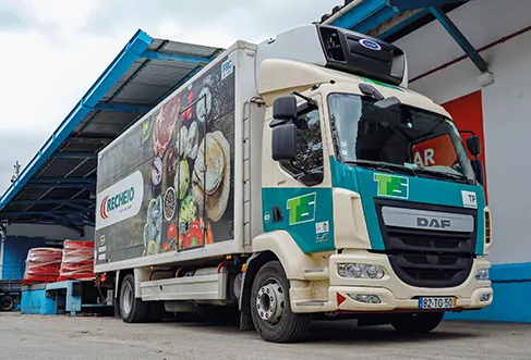 A deliver truck in a loading bay. On its side there is a photo of various fresh products and the Recheio logo. (photo)