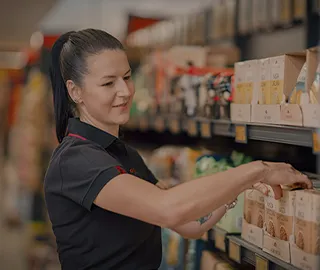 Employee arranging products in a supermarket shelf from Biedronka. (photo)