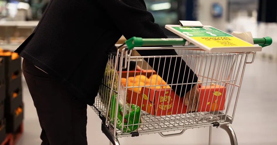 Customer placing a box of oranges into a shopping cart (photo)