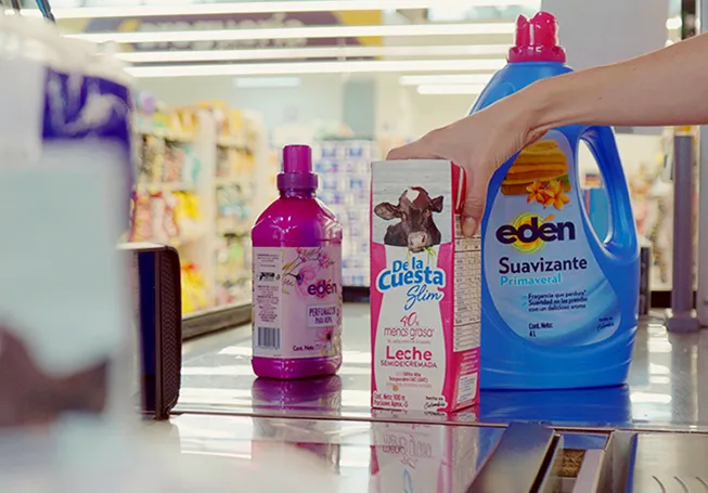 The hand of an employee reaching out to scan cleaning products and milk at the check-out counter (photo)