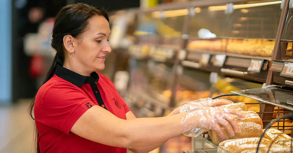 Biedronka employee putting loaves of bread on a shelf in the bakery (photo)