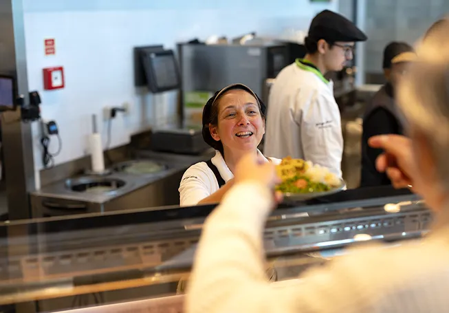 An employee handing a plate with food over a counter to a customer (photo)