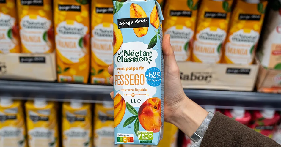 Close-up of someone holding a package of peach juice in front of a store shelf (photo)