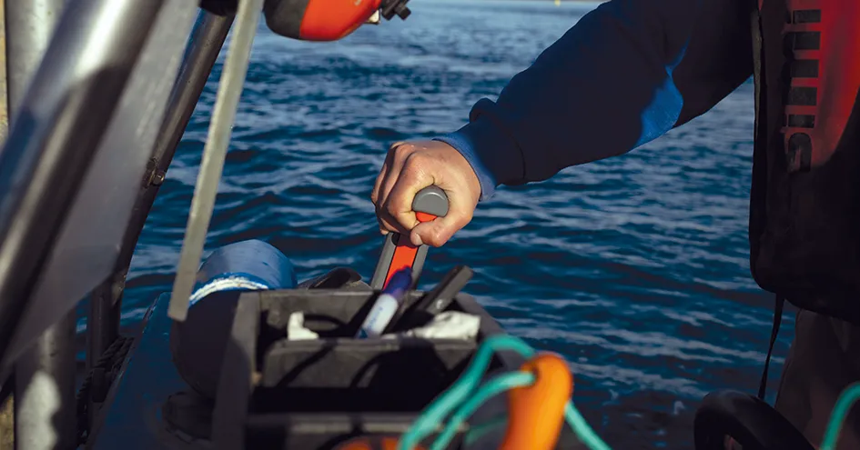 Close-up showing the arm and hand of a person holding the steering lever of a boat (photo)