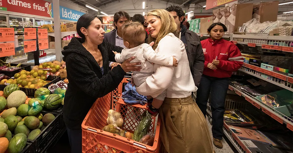 A woman hands over a baby to another woman in an Ara store full of customers (photo)