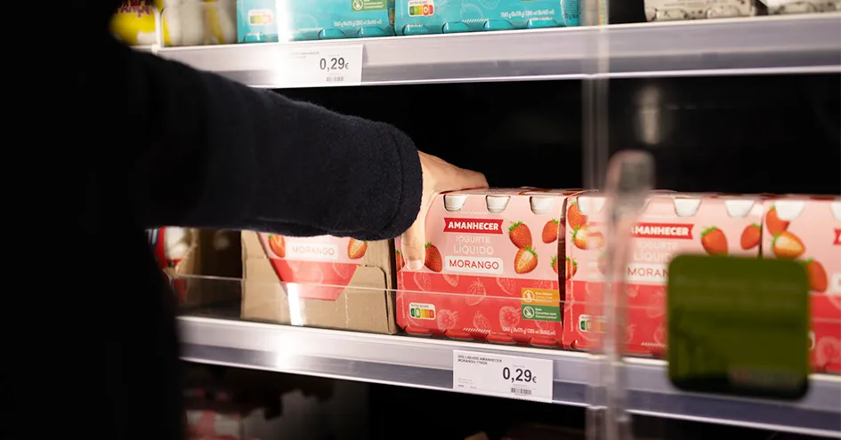 Close-up showing the arm and hand of a person selecting a package of strawberry yoghurts. (photo)