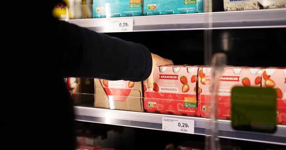 Close-up showing the arm and hand of a person selecting a package of strawberry yoghurts. (photo)