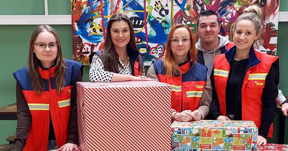 Biedronka employees in front of two large parcels in Christmas wrapping paper. (photo)