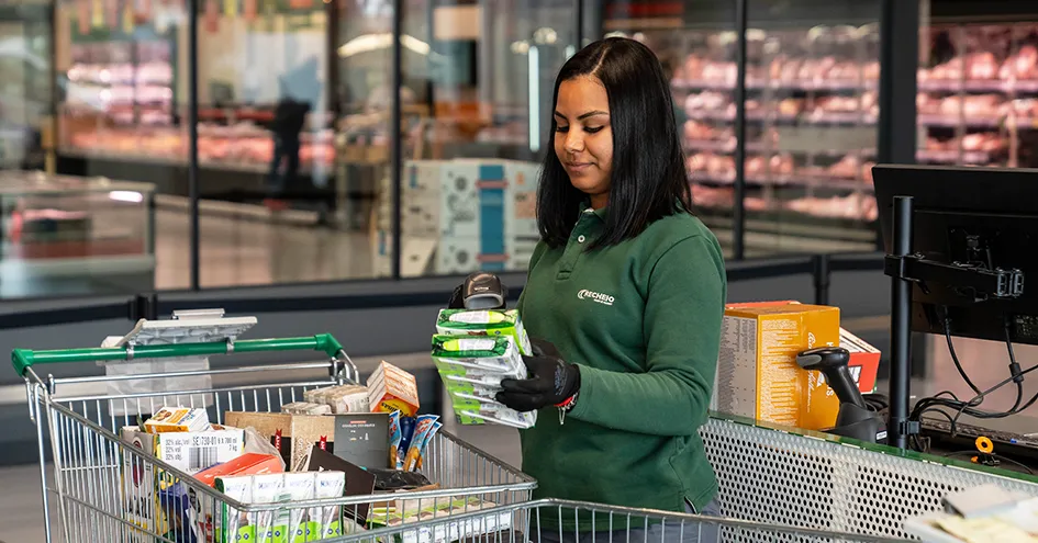 A Recheio employee scanning items directly from a full shopping cart at the check-out counter (photo)