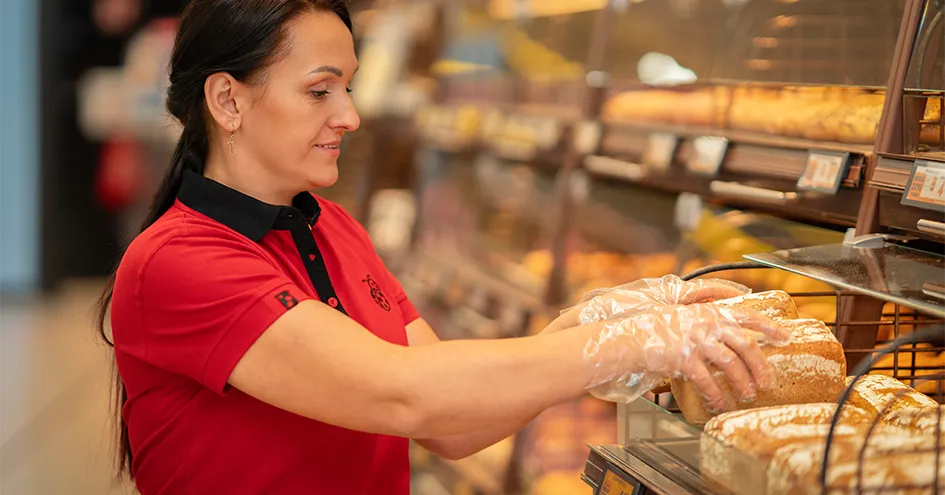 Biedronka employee putting loaves of bread on a shelf in the bakery (photo)