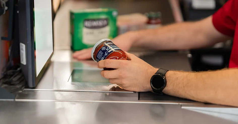 Close-up of a Biedronka employee scanning a glass container at check-out (photo)