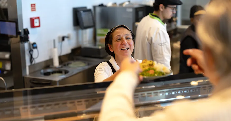 An employee handing a plate with food over a counter to a customer (photo)