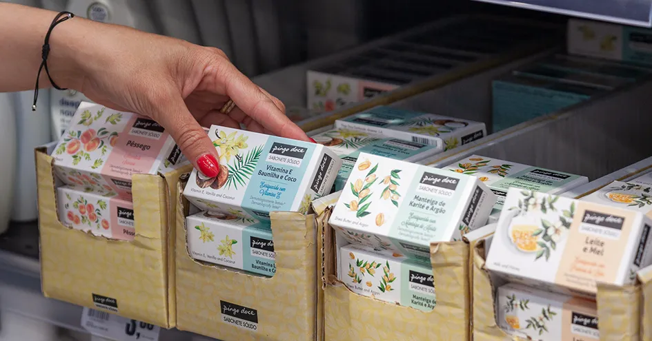 Close up of a woman taking a bar of soap from the shelf with various kinds of soaps from Pingo Doce. (photo)