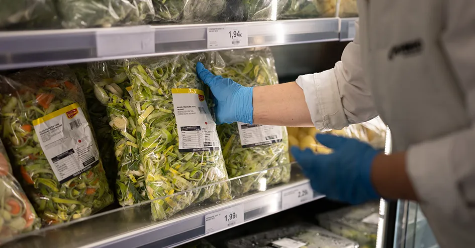 Employee placing a bag of pre-cut leeks on the shelf of the refrigerator at the store (photo)