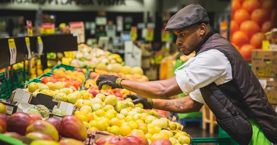 An employee restocking pears in the fresh produce section of a Pingo Doce store (photo)