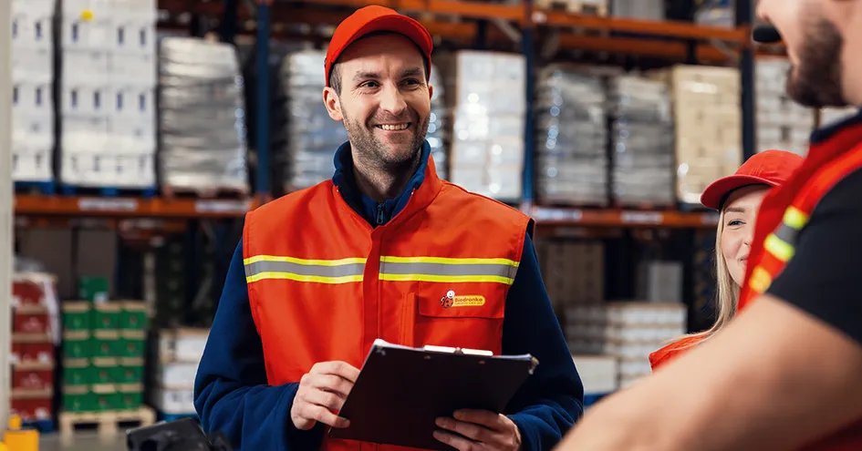 Three Biedronka employees in a distribution centre. One of them is holding a clipboard (photo)