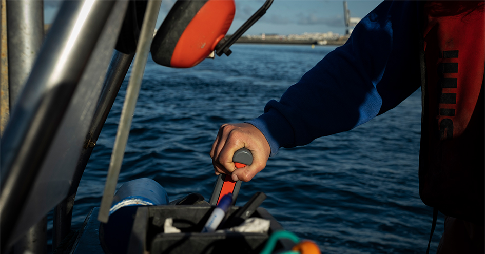 Grande plano da mão de uma pessoa enquanto conduz um barco (foto)