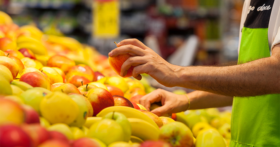 Um colaborador do Pingo Doce a empilhar maçãs numa loja (foto)