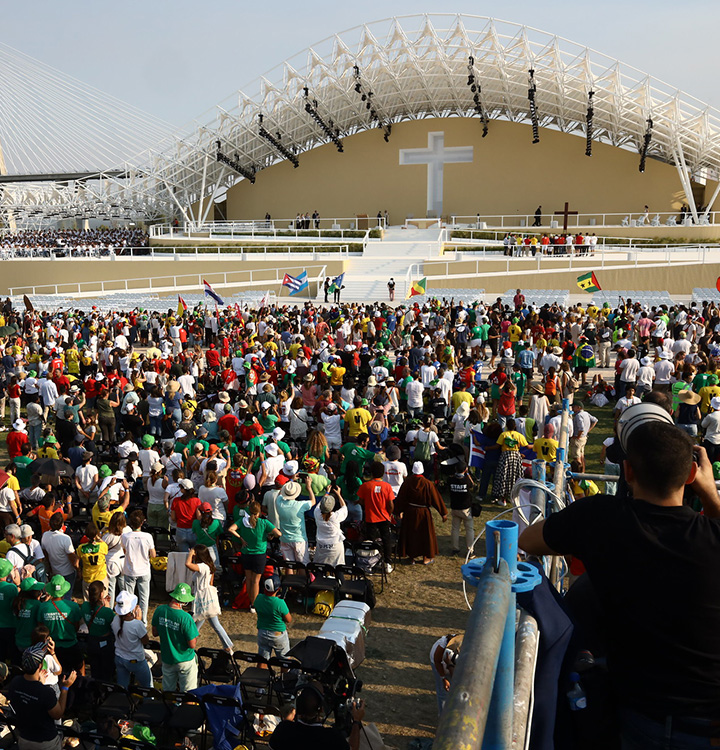 Uma multidão de pessoas em frente a um palco com uma cruz  (foto)