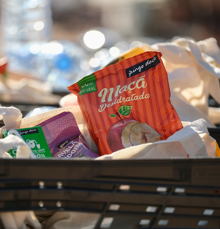 Uma caixa com produtos de Marca Própria Pingo Doce, como fatias de maçã desidratadas, leite e frutos secos (foto)