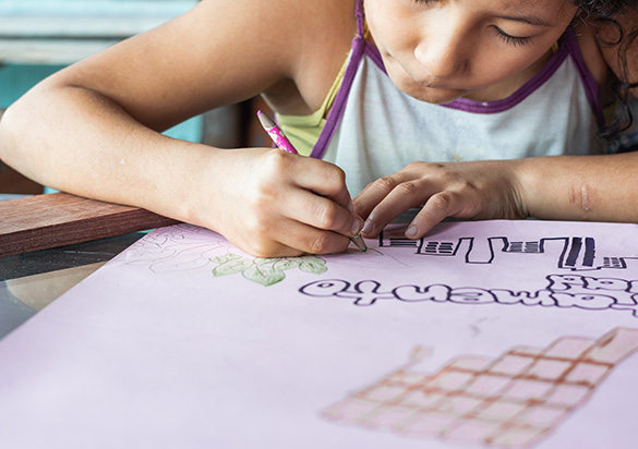 Criança a desenhar numa folha de papel (foto)