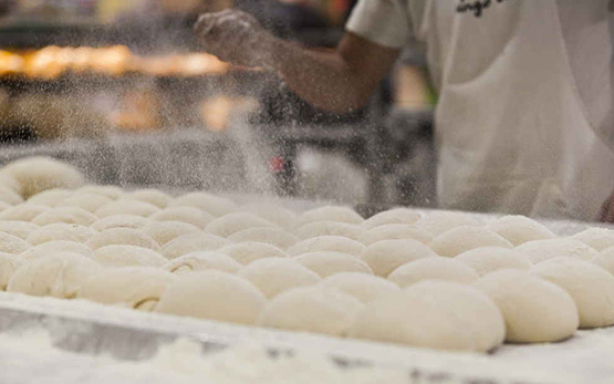 Colaborador a trabalhar em produtos de padaria e a espalhar farinha sobre eles (foto)