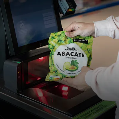 Uma pessoa a passar um pacote de abacates congelados no caixa de pagamento automático do Pingo Doce.