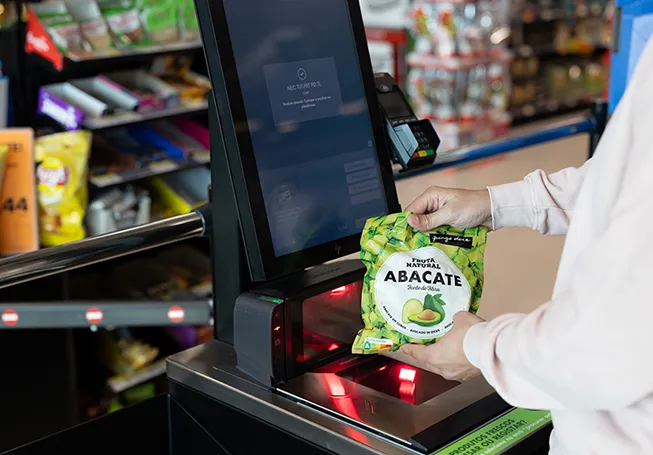 Uma pessoa a passar um pacote de abacates congelados no caixa de pagamento automático do Pingo Doce. (foto)
