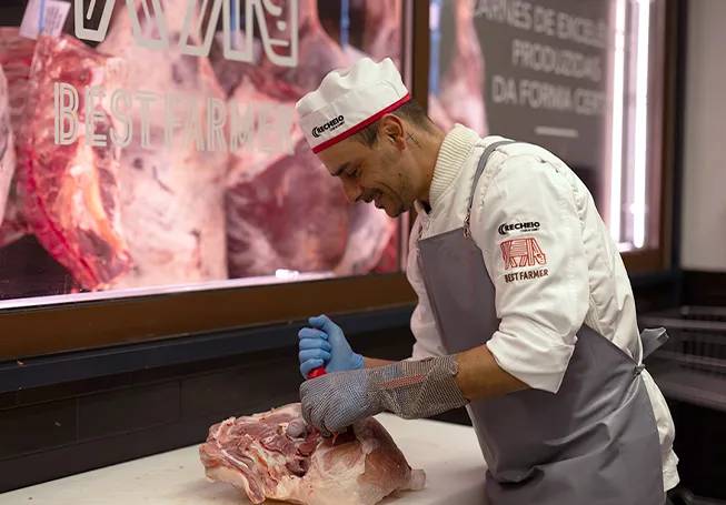 Um colaborador do Recheio a cortar um pedaço de carne no talho Best Farmer