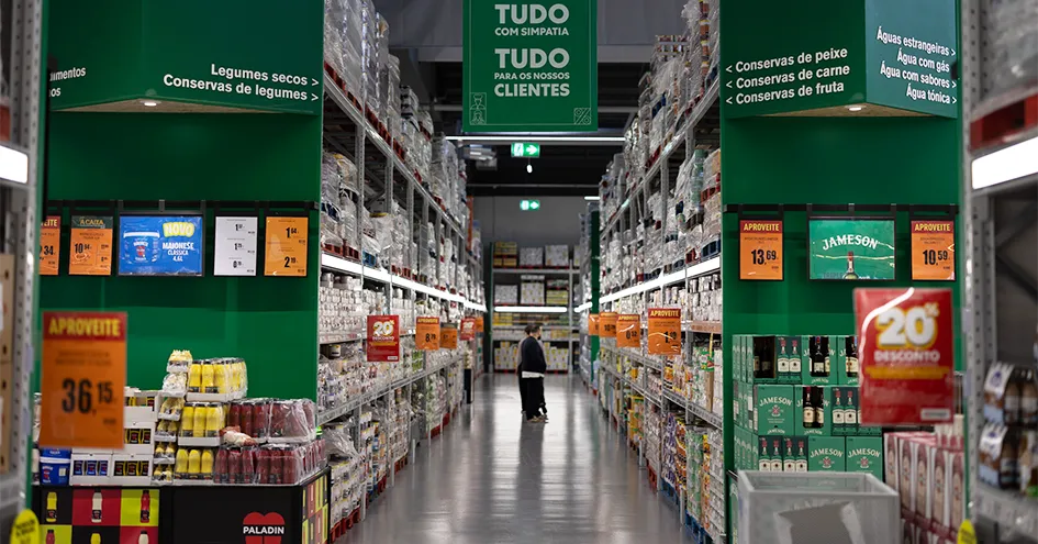 Corredor de conservas numa loja Recheio com clientes ao fundo (foto)